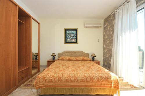 a bedroom with a bed and a large window at Apartments Balic in Sveti Stefan