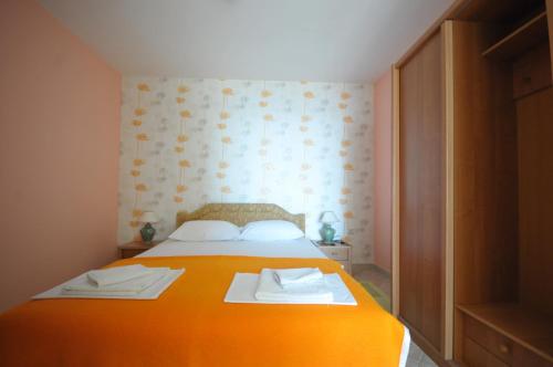 a bedroom with an orange bed with towels on it at Apartments Balic in Sveti Stefan