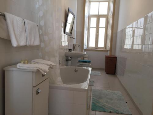 a white bathroom with a sink and a bath tub at Apartamento Casino Praia in Figueira da Foz