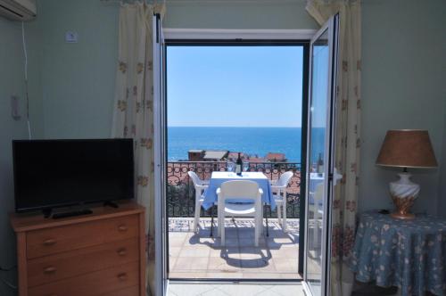 a room with a balcony with a table and a television at Apartments Balic in Sveti Stefan
