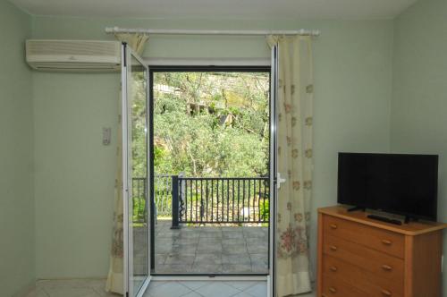 a living room with a sliding glass door with a television at Apartments Balic in Sveti Stefan
