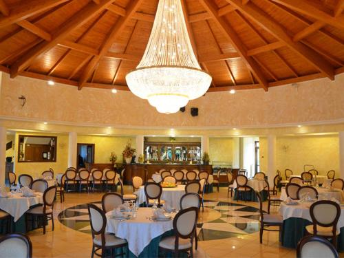 a banquet hall with tables and chairs and a chandelier at Hotel Valeria in Simbario