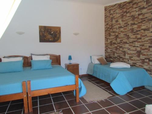 a bedroom with two beds and a brick wall at Quinta Do Forno in Vimeiro