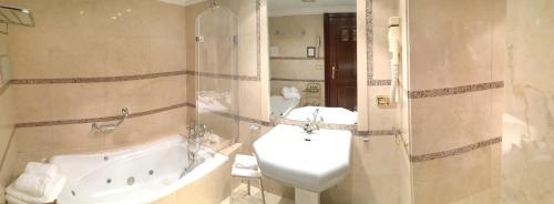a bathroom with a tub and a sink and a toilet at Hotel Maria Luisa in Burgos