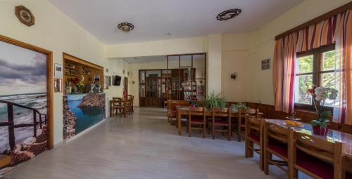 a dining room with tables and chairs and a large window at Hotel Eva Marina in Matala