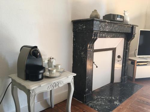 a room with a fireplace and a table with a tv at Appartements Plantagenet - Le 27 in Le Mans