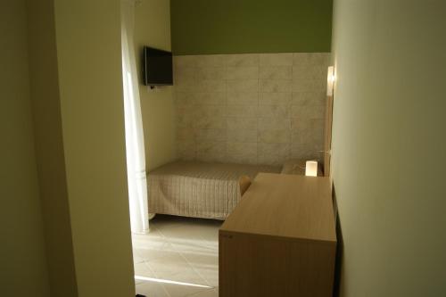 Habitación pequeña con cama y escritorio. en Guest House Golfo Xifonio, en Augusta