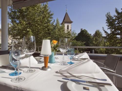 una mesa con copas de vino y servilletas en el balcón en Hotel MARIOTTO am Burghof en Lörrach