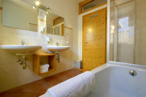 a bathroom with a tub and two sinks and a shower at Hotel Tschitscher in Nikolsdorf