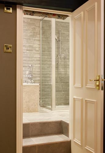 a bathroom with a shower and a bath tub next to a door at Ockenden Manor Hotel & Spa in Cuckfield