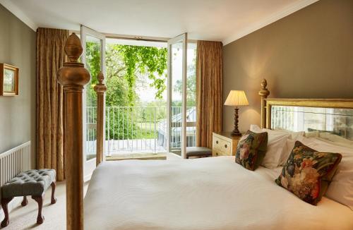 a bedroom with a bed and a large window at Ockenden Manor Hotel & Spa in Cuckfield