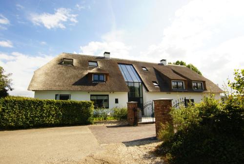 a house with a thatched roof with a driveway at Vakantiehuis Nijmegen in Erlekom