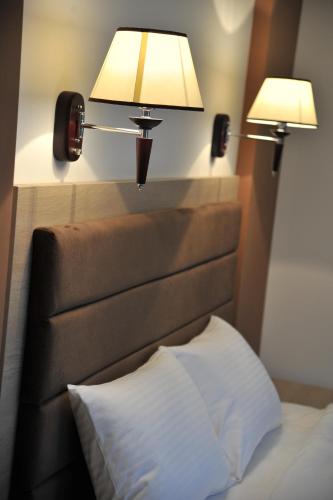 a bed with two lamps on top of a headboard at Hotel & Restaurant Ponte Bianco in Vranje