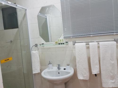 a bathroom with a sink and a shower with towels at Aliwal Villa Guest Lodge in Aliwal North