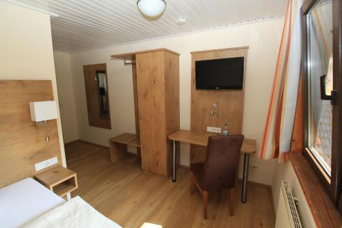 a room with a desk and a tv and a table at Waldhotel Albachmühle mit Albacher Stuben in Wasserliesch