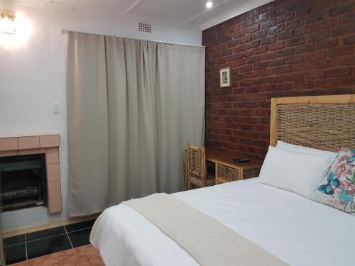a bedroom with a bed and a brick wall at Aliwal Villa Guest Lodge in Aliwal North