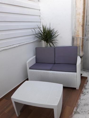 a white wicker chair and a table and a plant at Il sogno di Ele in Polignano a Mare