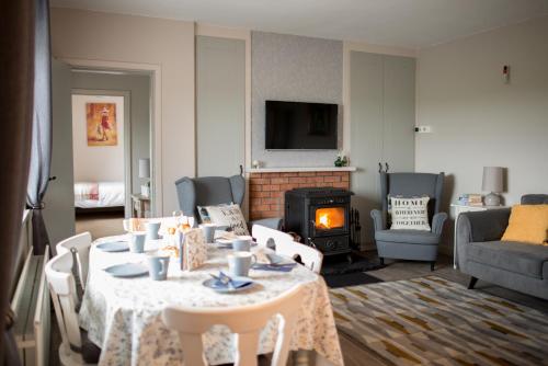 a living room with a table and a fireplace at Rose Meadow Cottage in Liscannor