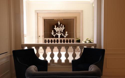 two chairs in front of a staircase with a chandelier at Grand Hotel Palace in Ancona