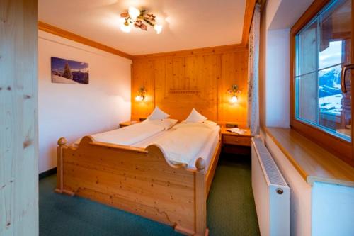 a bedroom with a large wooden bed with a window at Alpengasthof Rossmoos in Alpbach