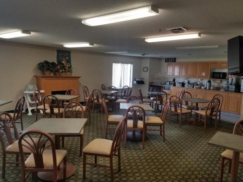 a dining room with tables and chairs and a kitchen at Syracuse Inn and Suites in Syracuse