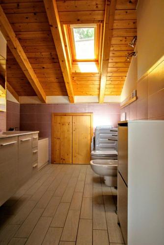 a bathroom with a toilet and a wooden ceiling at Residenza Christian in Gravedona