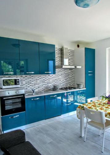 a kitchen with blue cabinets and a table in it at Residenza Christian in Gravedona