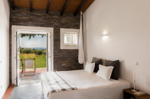 a bedroom with a large white bed and a window at Monte Falperras in Mourão