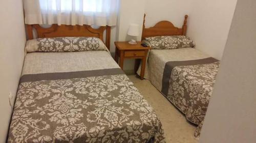Cette petite chambre comprend deux lits. une table de nuit dans l'établissement Pensión Campomar, à Cartaya