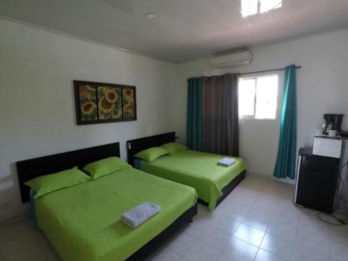1 dormitorio con 2 camas con sábanas verdes y ventana en Mary Hosting Sarie Bay, en San Andrés