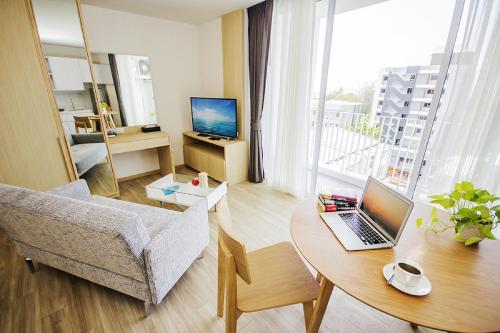 a living room with a table with a laptop on it at Karin hotel & Service apartment - SHA Extra Plus in Si Racha