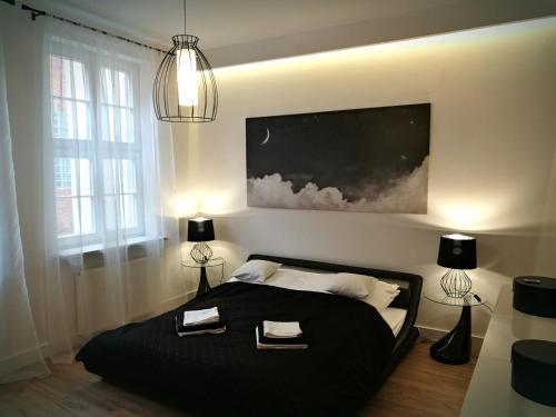 a bedroom with a black bed with two towels on it at Black&White Apartment- Wierzbowa 5 in Poznań
