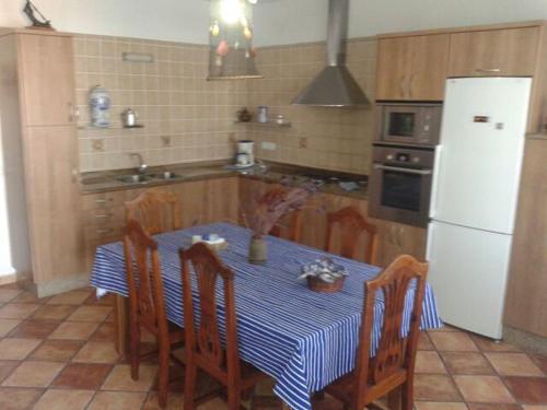 カレタ・デ・ファマラにあるEl Pescadorのキッチン(テーブル、椅子、白い冷蔵庫付)