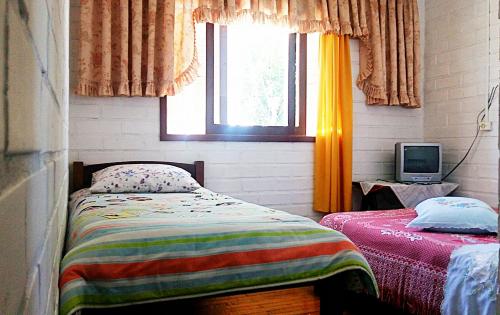a bedroom with a bed and a window and a television at Pousada Alvorada in Cambara do Sul