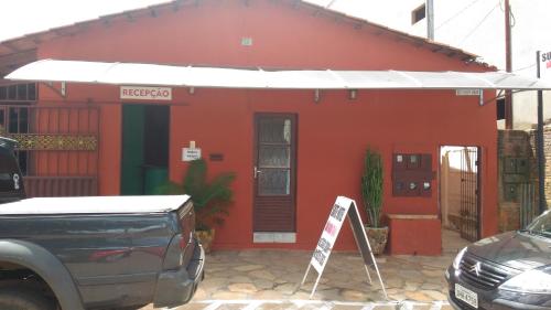 a red house with a sign in front of it at Suítes São Judas in Pirenópolis