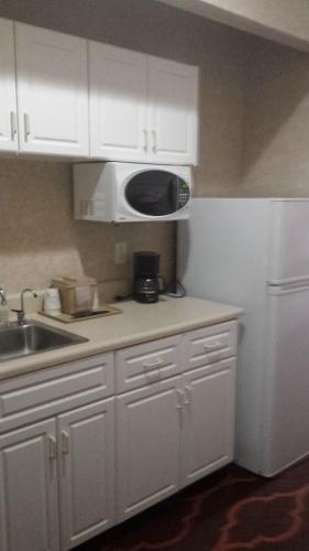 a kitchen with white cabinets and a microwave at Baymont by Wyndham Grovetown Augusta in Augusta