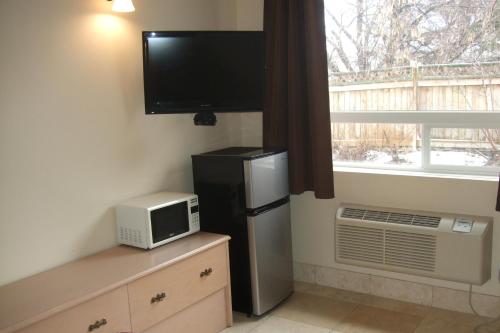 a kitchen with a refrigerator and a tv and a window at Trailside Inn in Lloydminster