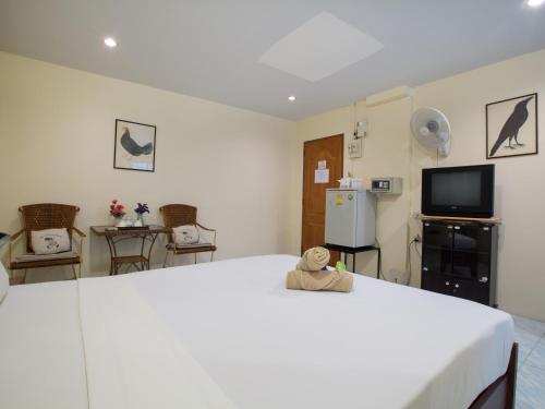 a bedroom with a large white bed and a tv at Stefan's Guesthouse in Jomtien Beach