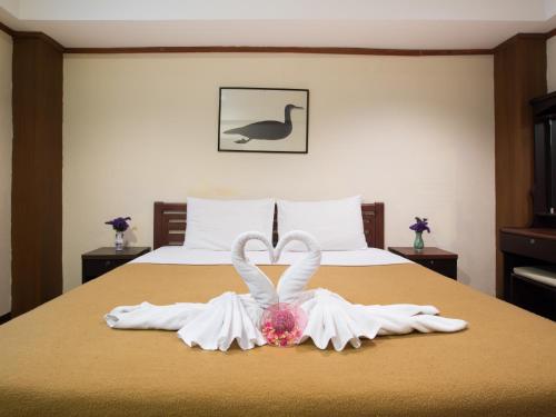 a bed with two white towels and a pair of swans at Stefan's Guesthouse in Jomtien Beach