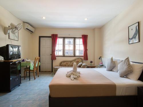 a hotel room with a large bed and a television at Stefan's Guesthouse in Jomtien Beach