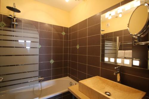 a bathroom with a tub and a sink and a mirror at Hôtel Serenada in Algajola