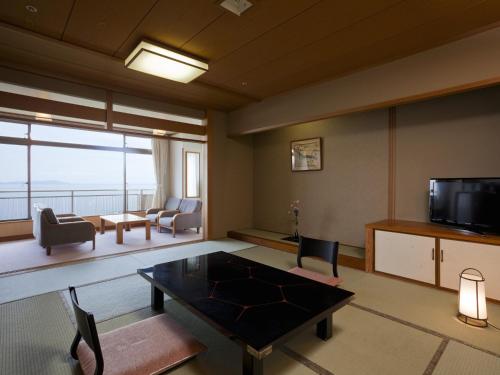 a living room with a table and a television at Hotel New Awaji in Sumoto