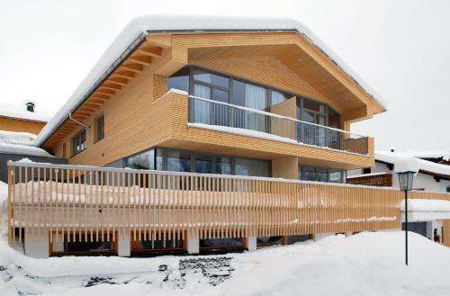 a house in the snow with a balcony at Pension Alpenfluh in Lech am Arlberg