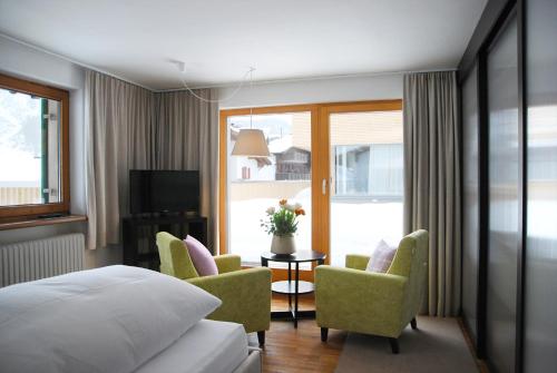 a hotel room with a bed and a table and chairs at Pension Alpenfluh in Lech am Arlberg