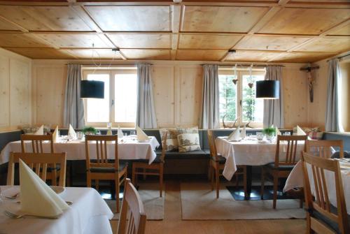 a dining room with tables and chairs and windows at Pension Alpenfluh in Lech am Arlberg