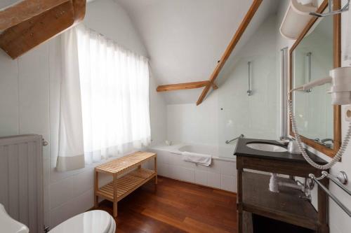 a bathroom with a sink and a bath tub at Hotel Heritage in De Haan