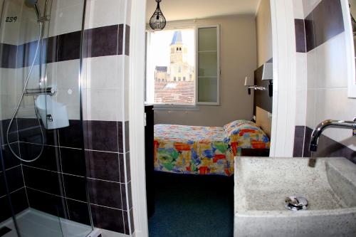 a bathroom with a shower and a bed and a sink at Hotel de la Basilique in Paray-le-Monial