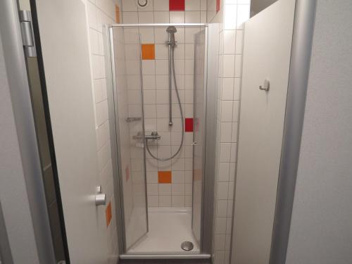 een douche met een glazen deur in de badkamer bij Jugendherberge List in List