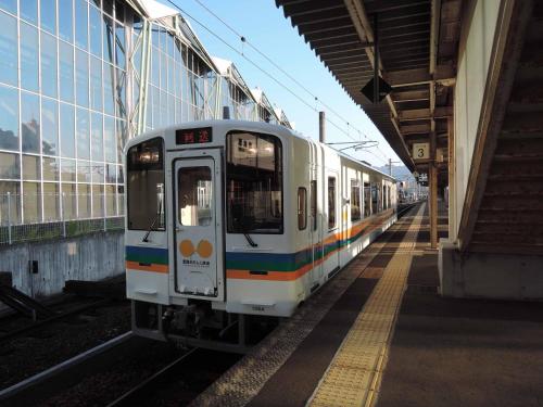 a white train is parked at a train station at Hotel King in Izumi