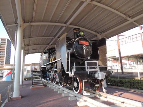 a black train on display under a train station at Hotel King in Izumi